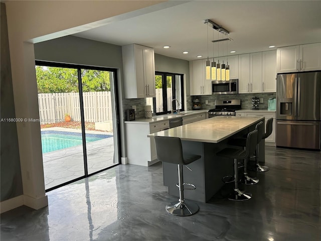 kitchen with a center island, decorative light fixtures, white cabinetry, appliances with stainless steel finishes, and tasteful backsplash