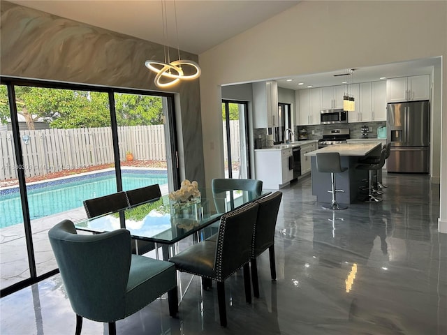 kitchen featuring appliances with stainless steel finishes, a center island, hanging light fixtures, white cabinets, and decorative backsplash