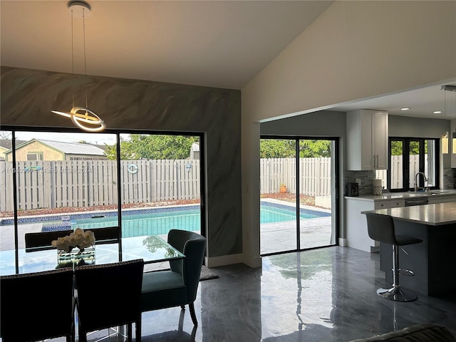 dining space with lofted ceiling, sink, and a healthy amount of sunlight