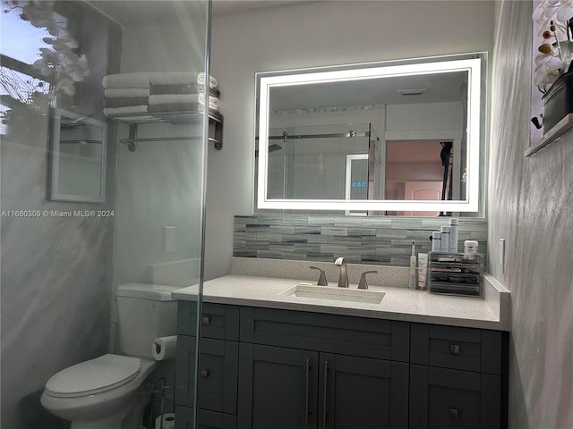 bathroom with vanity, toilet, decorative backsplash, and a shower