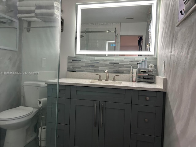 bathroom featuring vanity, decorative backsplash, and toilet