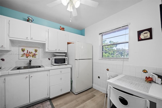 kitchen featuring white appliances, tile countertops, sink, and white cabinets