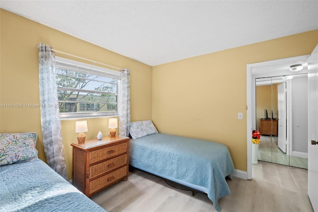 bedroom with light hardwood / wood-style flooring, a textured ceiling, and a closet