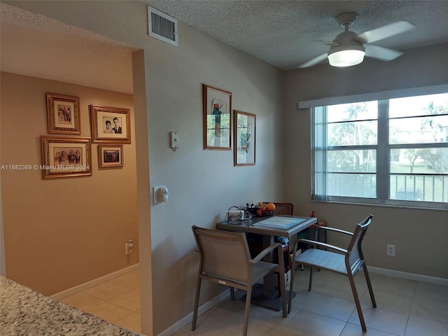 tiled dining space featuring ceiling fan and a textured ceiling