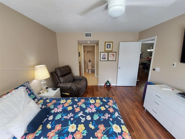 bedroom with dark hardwood / wood-style flooring, a textured ceiling, connected bathroom, and ceiling fan