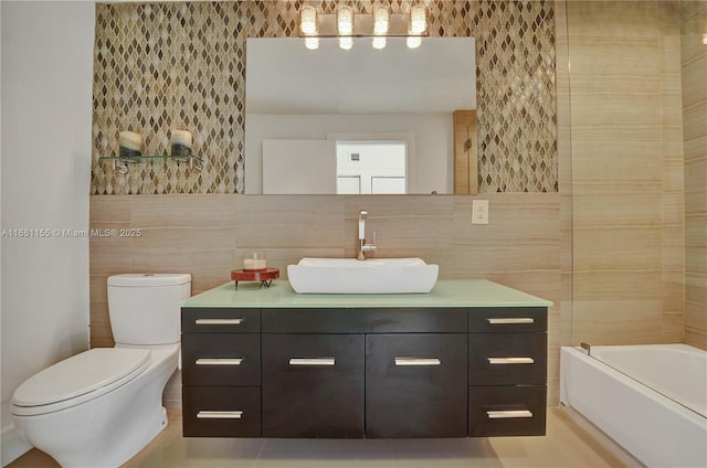 bathroom with toilet,  shower combination, tile walls, and vanity