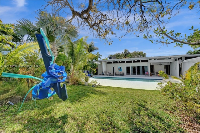 rear view of house featuring a patio area, stucco siding, an outdoor pool, and a yard