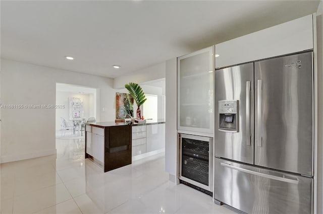 kitchen featuring light tile patterned floors, beverage cooler, baseboards, stainless steel fridge with ice dispenser, and modern cabinets