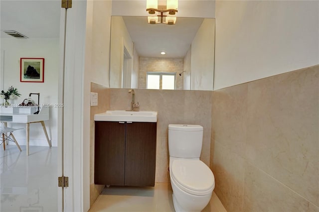 bathroom featuring visible vents, tile walls, toilet, and vanity