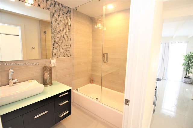 bathroom with tasteful backsplash, combined bath / shower with glass door, tile walls, and vanity