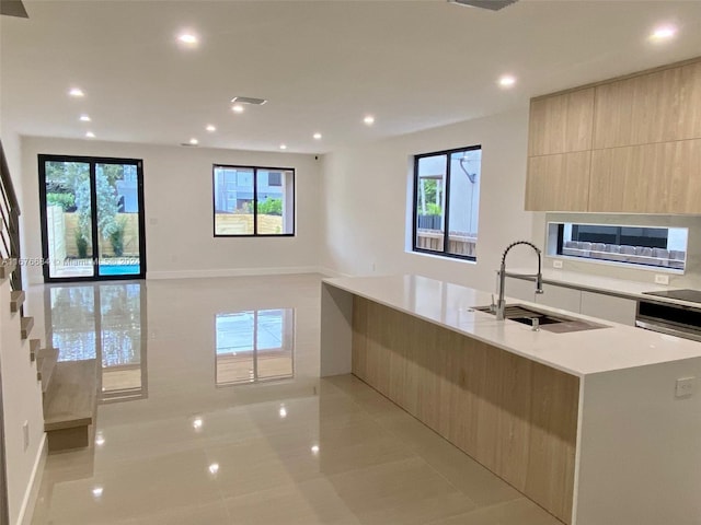 kitchen with black electric stovetop, a large island, light tile patterned floors, and sink