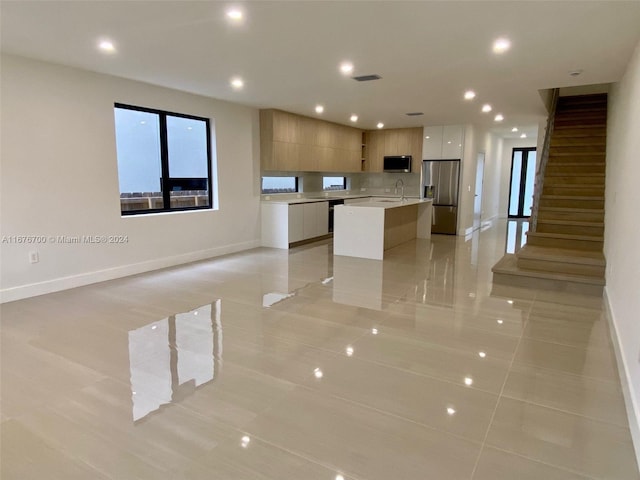 kitchen featuring white cabinetry, a center island with sink, light tile patterned floors, and appliances with stainless steel finishes