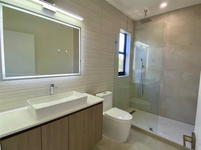 bathroom with vanity, toilet, tiled shower, and tile walls