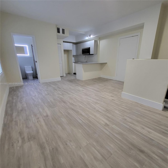 unfurnished living room featuring light hardwood / wood-style flooring and sink