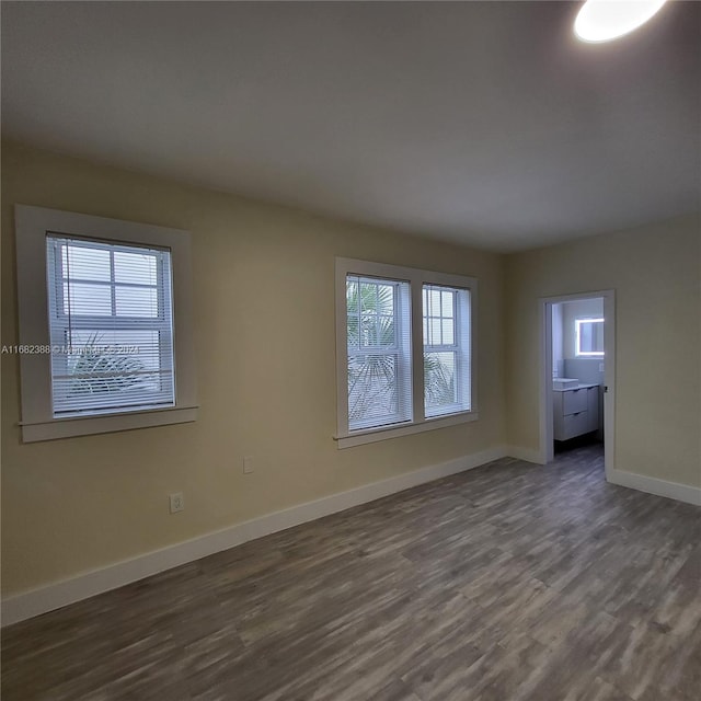 empty room with a wealth of natural light and dark hardwood / wood-style flooring