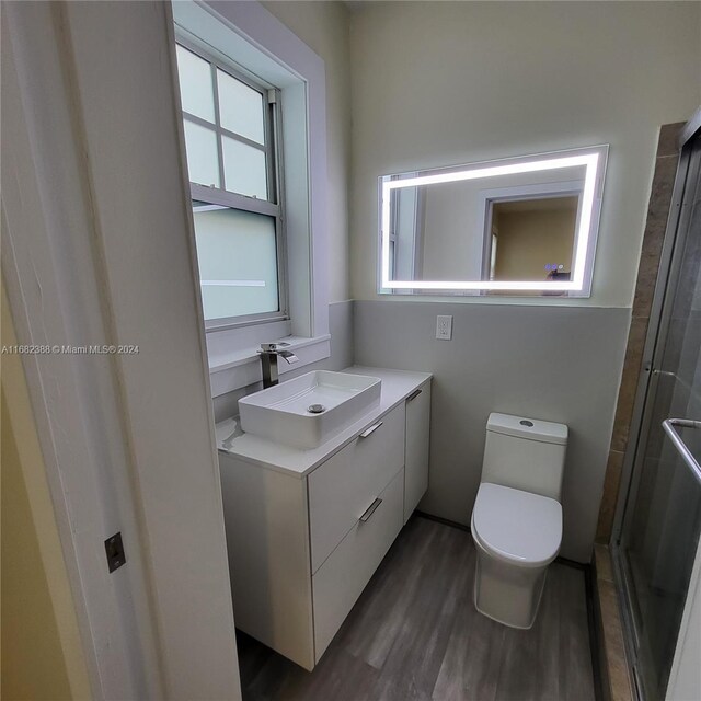 bathroom featuring vanity, toilet, an enclosed shower, and hardwood / wood-style floors