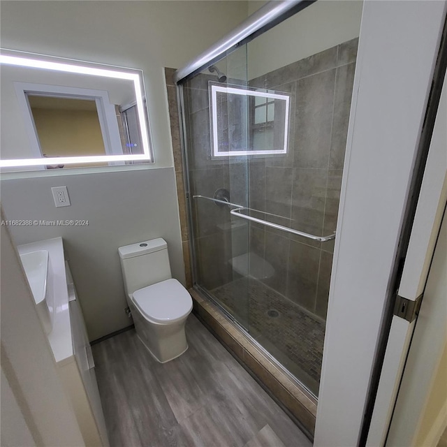 bathroom featuring hardwood / wood-style floors, toilet, and walk in shower