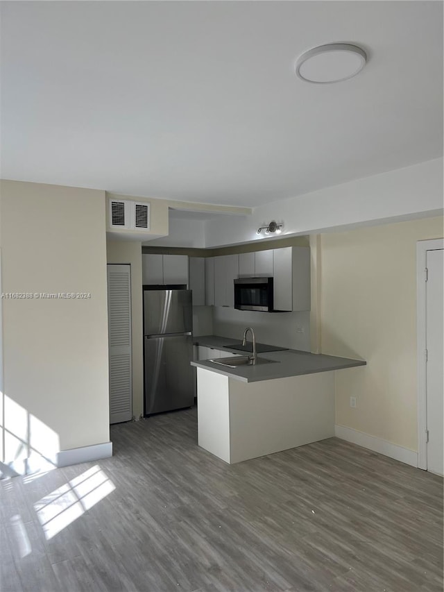 kitchen featuring kitchen peninsula, gray cabinetry, stainless steel appliances, sink, and light wood-type flooring