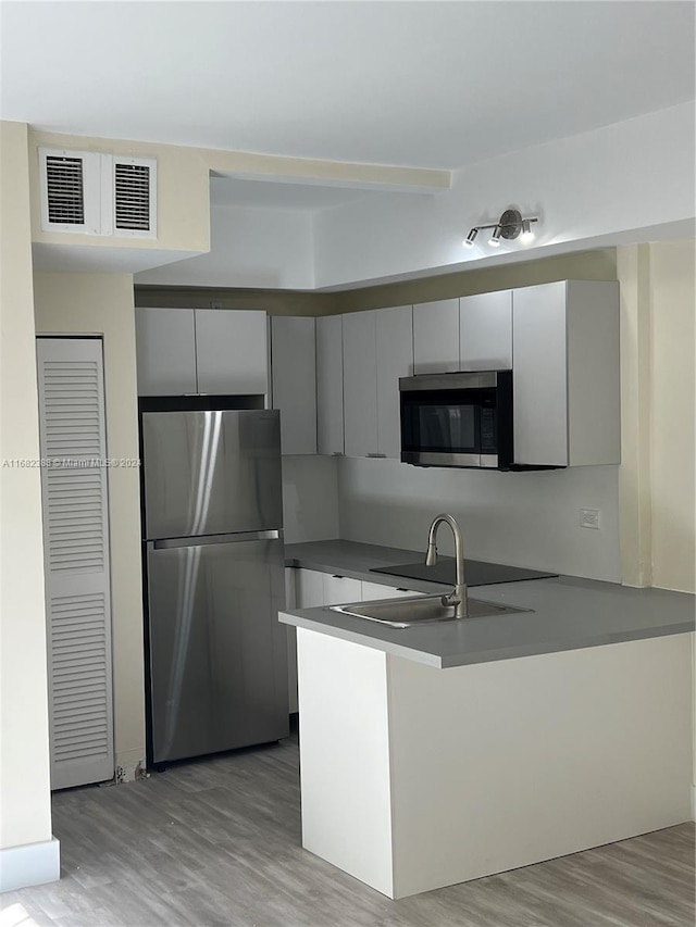 kitchen featuring light hardwood / wood-style floors, stainless steel appliances, sink, and kitchen peninsula