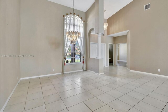 unfurnished room with light tile patterned floors, high vaulted ceiling, and an inviting chandelier