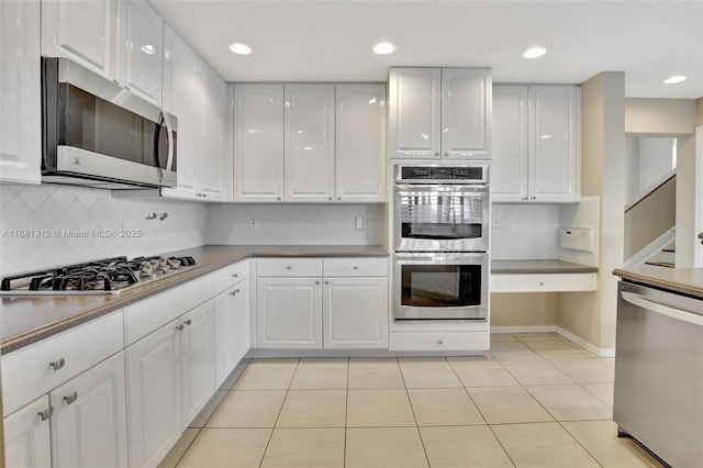 kitchen with light tile patterned flooring, white cabinetry, appliances with stainless steel finishes, and tasteful backsplash