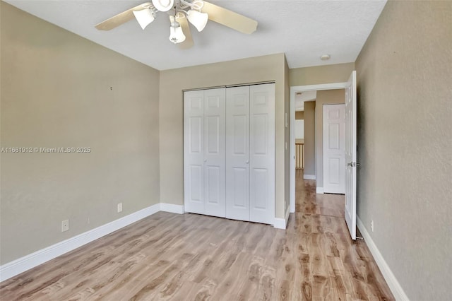 unfurnished bedroom featuring ceiling fan, light hardwood / wood-style floors, and a closet