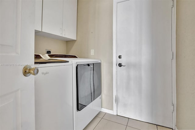 clothes washing area with washer and clothes dryer, light tile patterned floors, and cabinets