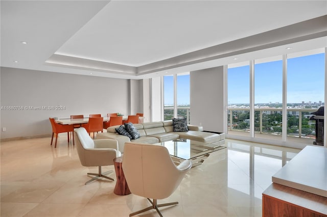 living room with light tile patterned flooring, a tray ceiling, and floor to ceiling windows