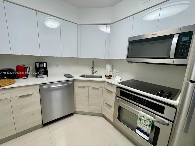 kitchen featuring stainless steel appliances, sink, light brown cabinetry, and light tile patterned floors