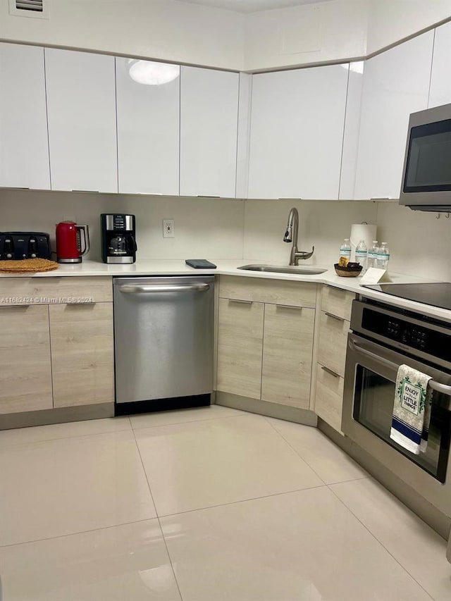 kitchen featuring appliances with stainless steel finishes, sink, and light tile patterned floors