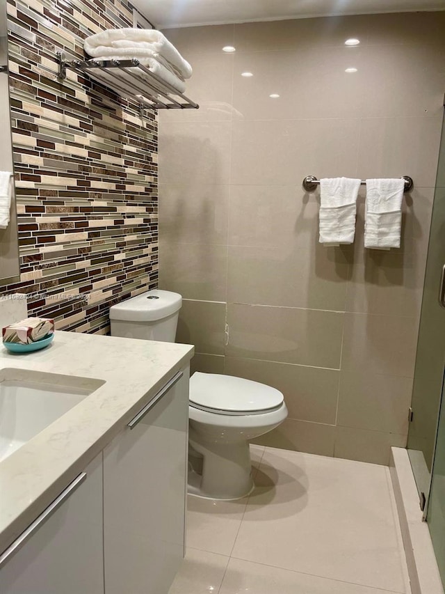 bathroom with tile patterned floors, toilet, backsplash, vanity, and tile walls