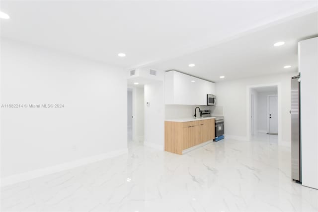 kitchen featuring stainless steel appliances, light brown cabinetry, sink, and white cabinets