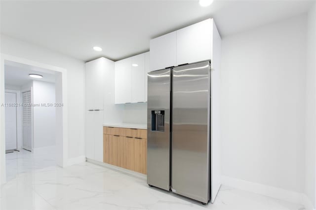 kitchen featuring white cabinetry and stainless steel refrigerator with ice dispenser