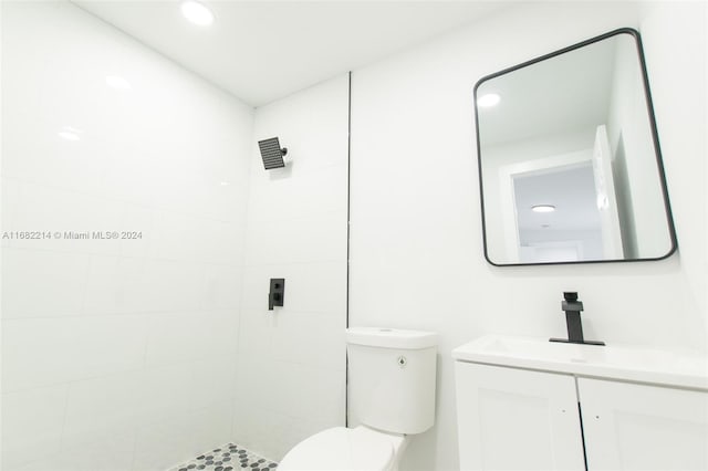 bathroom with toilet, vanity, and a tile shower