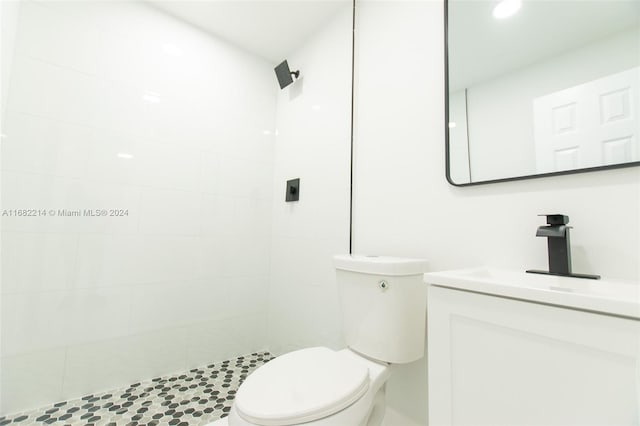 bathroom with toilet, vanity, and a tile shower