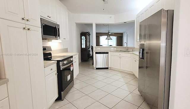 kitchen with appliances with stainless steel finishes, sink, pendant lighting, white cabinets, and light tile patterned flooring