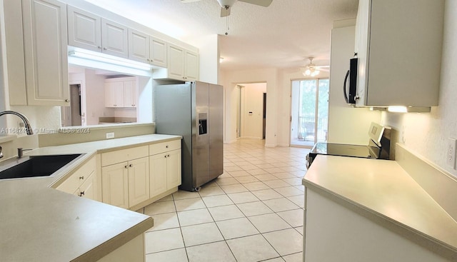 kitchen with appliances with stainless steel finishes, light tile patterned floors, white cabinetry, and sink