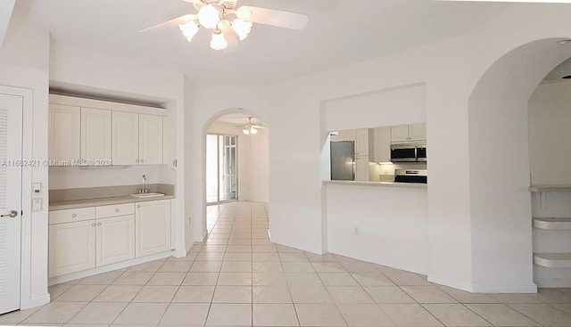 kitchen with ceiling fan, sink, light tile patterned flooring, and stainless steel appliances