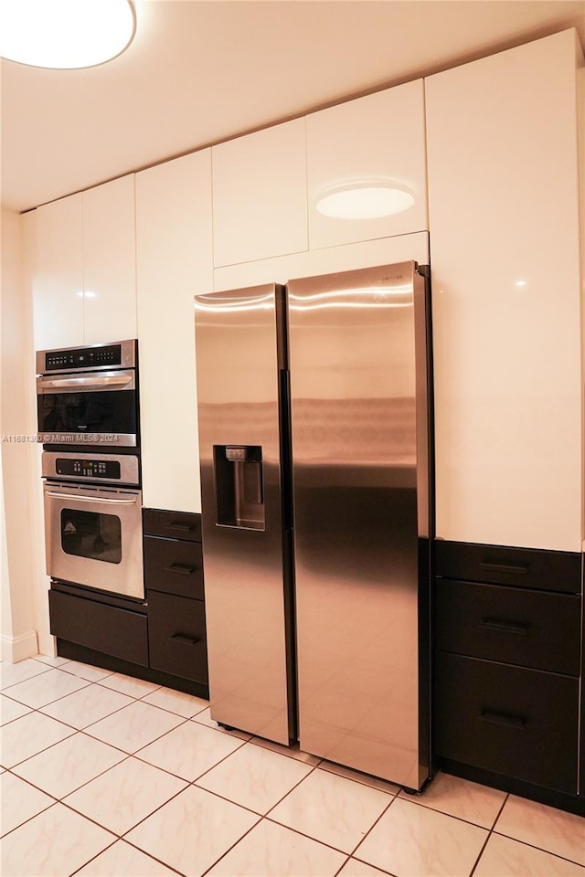 kitchen with white cabinets, stainless steel appliances, and light tile patterned floors