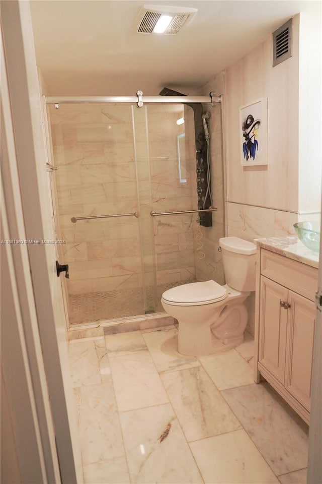 bathroom with a shower with door, vanity, and toilet