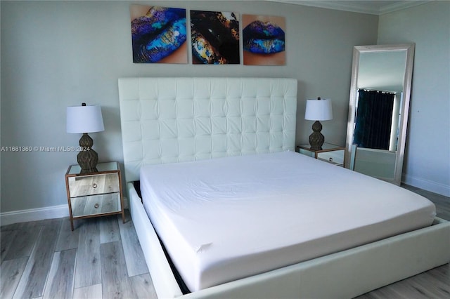 bedroom with ornamental molding and wood-type flooring