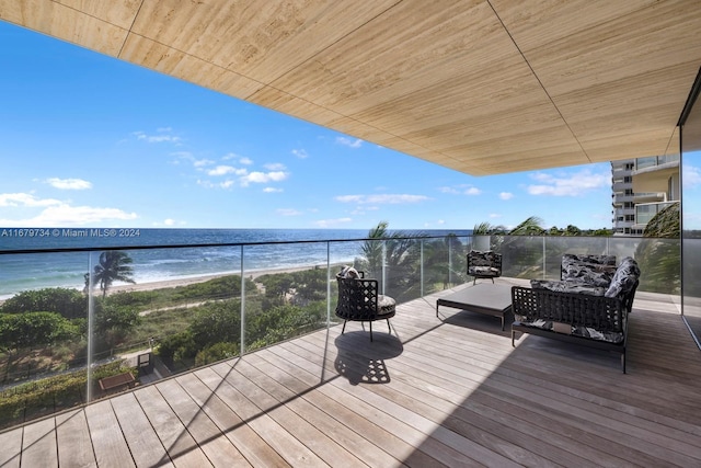 wooden terrace with a water view and a view of the beach