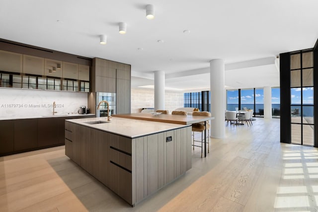 kitchen with light hardwood / wood-style floors, sink, a large island with sink, and a breakfast bar area