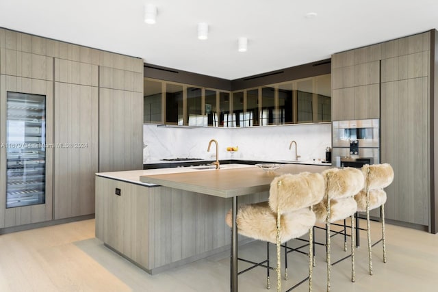 kitchen with tasteful backsplash, a breakfast bar, a spacious island, and sink