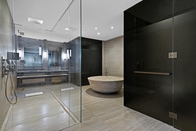 bathroom featuring vanity, plus walk in shower, and tile walls