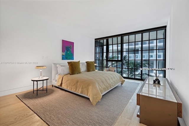 bedroom with floor to ceiling windows and wood-type flooring