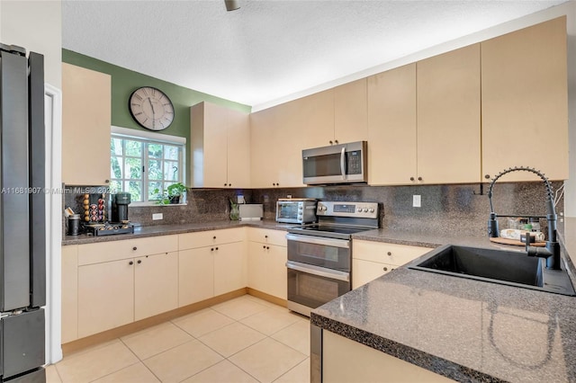 kitchen featuring sink, cream cabinetry, stainless steel appliances, and backsplash