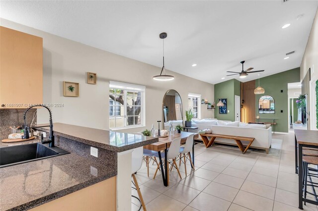 kitchen featuring kitchen peninsula, hanging light fixtures, a breakfast bar, vaulted ceiling, and sink