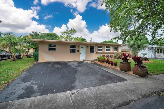 ranch-style home with aphalt driveway, a front lawn, and stucco siding