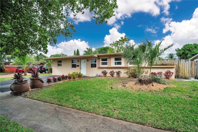 single story home with stucco siding, fence, and a front yard